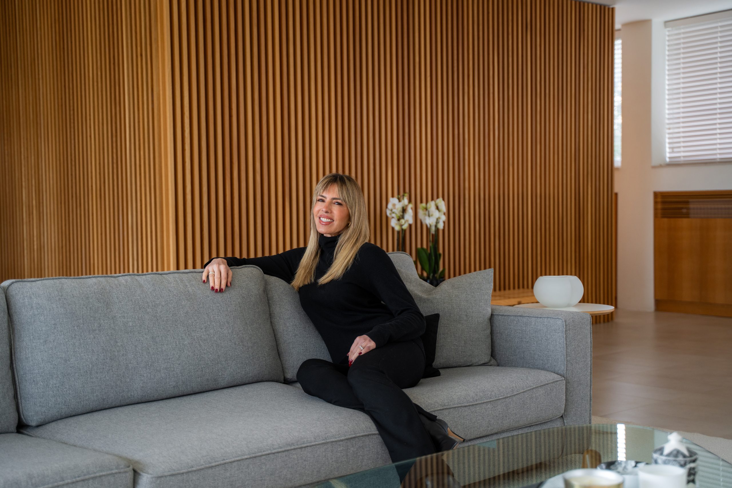 Esther Sarphatie smiling while seated on a gray couch.